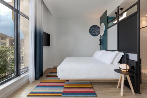 a bedroom with a white bed and a large window at Aloft Hotel, By Marriott in Dijon
