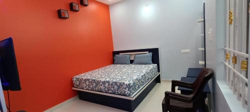 a small bedroom with a bed with an orange wall at Sathyam Resorts in Dharmapuri