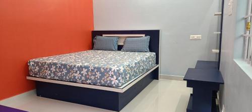 a small bed in a room with an orange wall at Sathyam Resorts in Dharmapuri