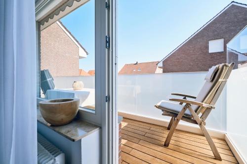 a balcony with a wooden bowl and a chair at Vier Häuser in Norderney