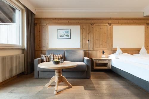 カルテルベッロにあるHotel Sandのベッドとテーブルとソファのあるホテルの部屋