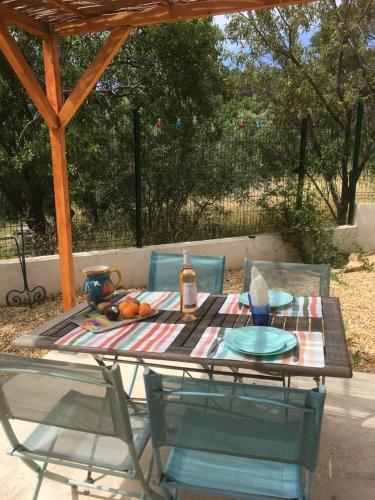 - une table de pique-nique avec 2 chaises et une bouteille de vin dans l'établissement La petite maison, mer et colline, à Carqueiranne