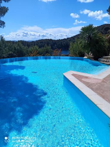 une piscine bleue avec des montagnes en arrière-plan dans l'établissement Appartement lumineux, proche mer et lac, à Saint-Raphaël