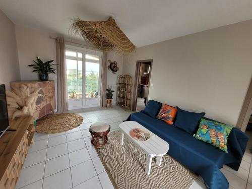 a living room with a blue couch and a table at Le Capestang in Canet-en-Roussillon