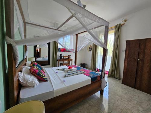 sypialnia z łóżkiem z baldachimem w obiekcie Zanzicrown w mieście Nungwi