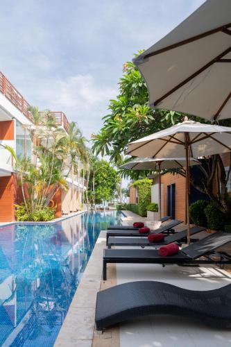 a pool at the resort with lounge chairs and umbrellas at La Flora Resort Patong in Patong Beach