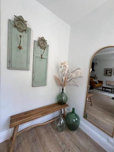 une pièce avec un banc, un miroir et des vases dans l'établissement Appartement La Caresse de l’Amarante, à Mortagne-au-Perche