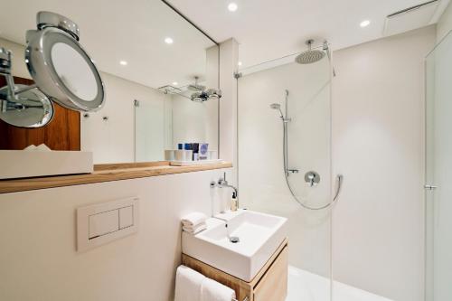 a white bathroom with a sink and a shower at Vier Häuser in Norderney