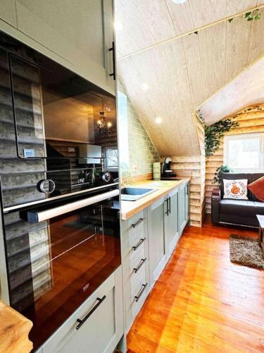 a kitchen with white cabinets and a couch in a room at Squirrel Hideaway with Hot Tub in Formby, Liverpool in Formby