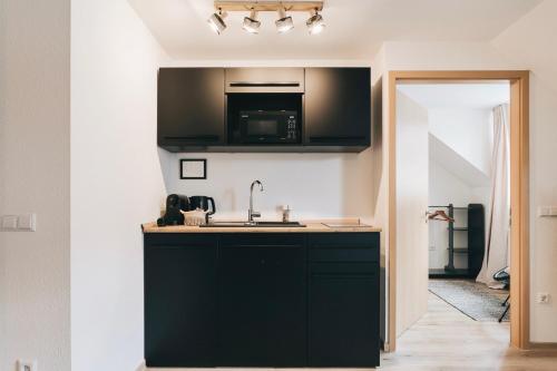 a kitchen with black cabinets and a sink at Gemütliche Oase in der Altstadt in Löbau