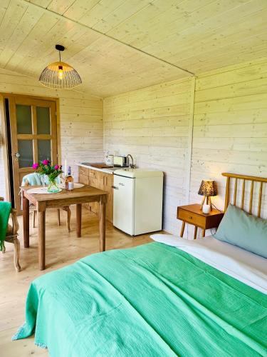a room with a bed and a refrigerator and a table at Sakura Tiny house in National park,salty pool in Staré Křečany