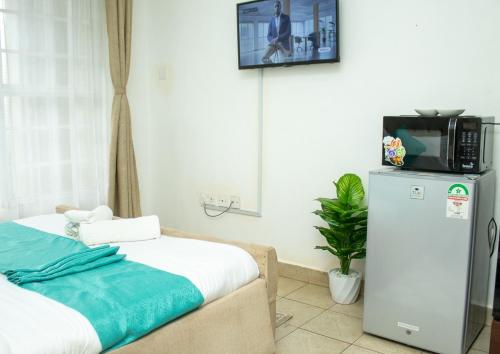 a room with a bed and a tv on a refrigerator at Belaire Airbnb Ruaka 2 in Ruaka