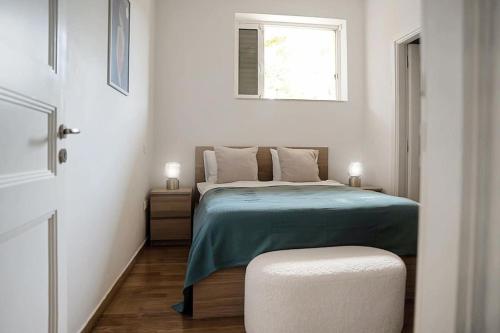 a bedroom with a bed with a blue blanket and a window at Varkiza Seaside and Views Retreat with Jacuzzi in Vari