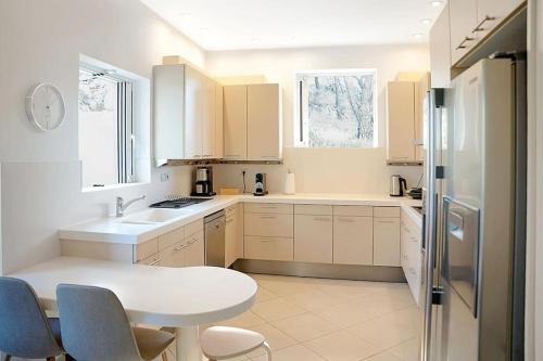 a white kitchen with a table and a refrigerator at Varkiza Seaside and Views Retreat with Jacuzzi in Vari