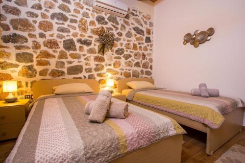 a bedroom with two beds and a stone wall at Villa in the Woods in Kolimbia