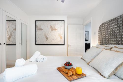 a white bed with a tray of donuts on it at Rare 4beds Townhouse in Kensington with Patio in London