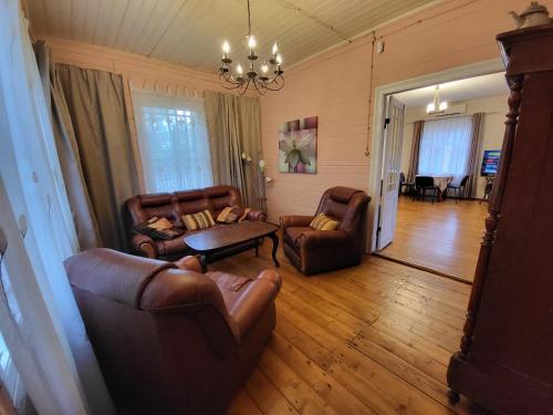 a living room with leather furniture and a chandelier at Summer cottage in Jurmala in Jūrmala