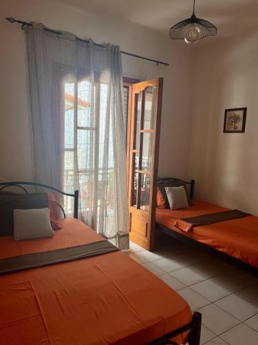 two beds are in a room with a window at Eleni Antonouli Rooms in Kokkino Nero