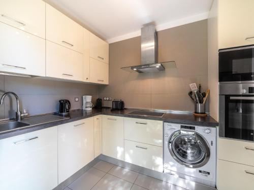 une cuisine avec des armoires blanches et une laveuse et une sécheuse dans l'établissement Holiday Home Le Rayolet by Interhome, à Le Brusc