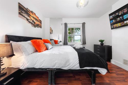 a bedroom with a large bed with orange and white pillows at The Hogwarts Retreat - Cinema Room - in Watford