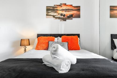 a bedroom with a bed with white sheets and orange pillows at The Hogwarts Retreat - Cinema Room - in Watford