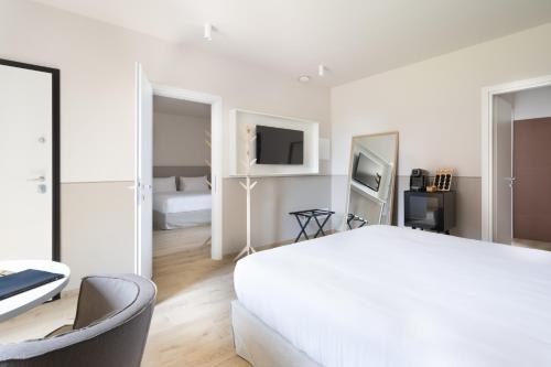 a white bedroom with a large bed and a chair at Villa Il Platano in Como