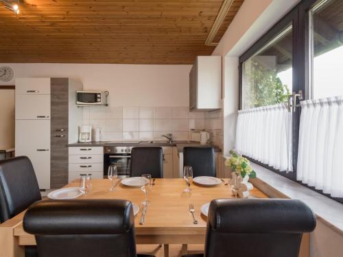 a kitchen and dining room with a wooden table and chairs at Apartment Eifelnatur - Haus 2-1 by Interhome in Immerath