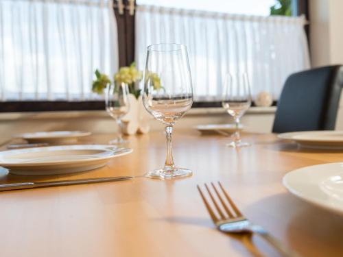 a table with three wine glasses and plates on it at Apartment Eifelnatur - Haus 2-1 by Interhome in Immerath