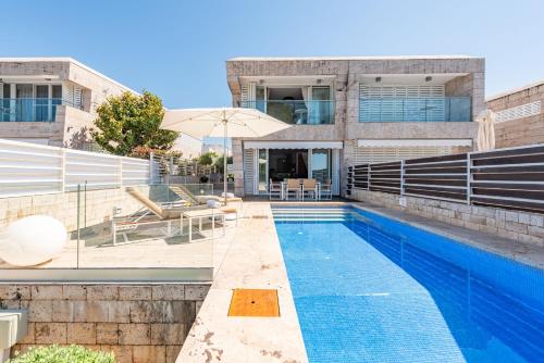 a house with a swimming pool in front of a building at Villa Olea ZadarVillas in Petrcane