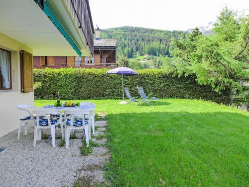 a table and chairs and an umbrella in a yard at Apartment Chalet Papillon by Interhome in Bürchen