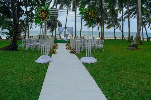 a aisle with white chairs and flowers in a field at Cocoa Luxury Resort, Nyali, Mombasa in Mombasa