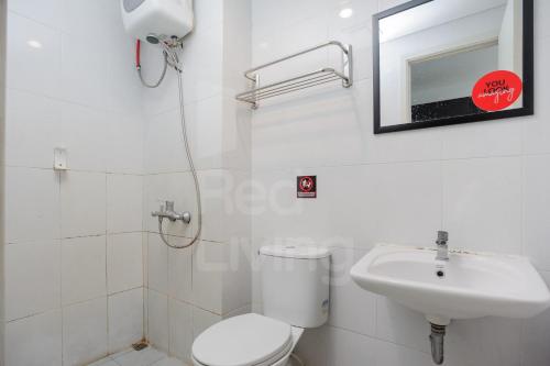 a white bathroom with a toilet and a sink at RedLiving Apartment Patra Land Urbano - Alfa Rooms Tower East in Bulanbulan