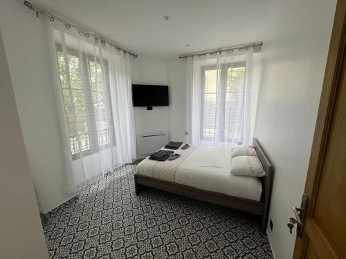 a bedroom with a bed and two windows at L'étoile de Seine 77 Appartement 5 in Dammarie-lès-Lys