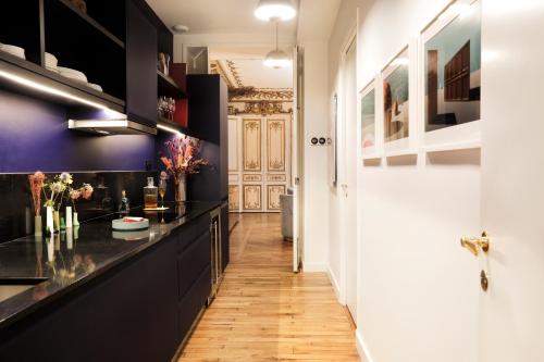 eine Küche mit schwarzen Schränken und Holzböden in der Unterkunft Beauquartier - Madeleine in Paris