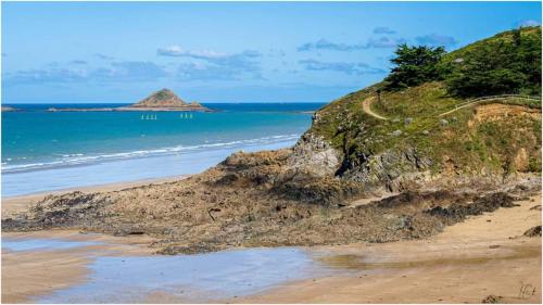 a beach with a dirt road and the ocean at Le clos du Verdelet vue mer piscine in Planguenoual