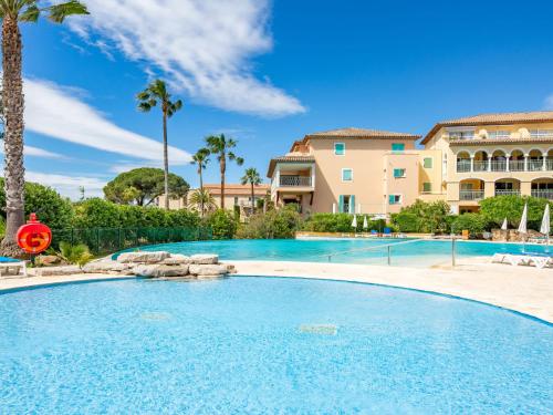 - une piscine dans un complexe avec des palmiers et un bâtiment dans l'établissement Apartment Les Rivages des Issambres-4 by Interhome, aux Issambres