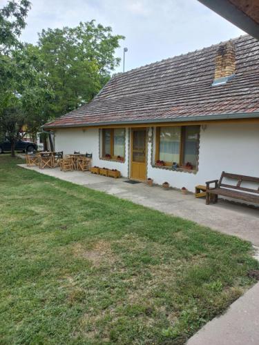 a white building with wooden benches in a yard at Salaš Trikić in Aleksandrovo