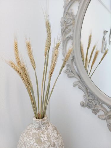 eine Vase mit Weizenspießen vor einem Spiegel in der Unterkunft Εvi Evan Hotel in Galissas