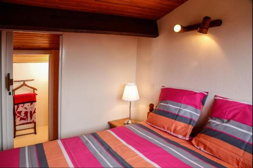 a bedroom with a bed with pink and orange pillows at Résidence d'Aquitaine in Vieux-Boucau-les-Bains