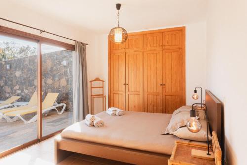 a bedroom with a bed and a balcony at Villa Upupa in La Oliva