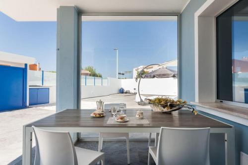 Un comedor con mesa y sillas y una gran ventana. en Leonida's Home - Shared Pool, Jacuzzi and beach 150mt, en Su Forti