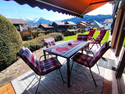 a table and chairs on a patio with mountains in the background at Der Sonnenhof - Ferienwohnungen in Obermaiselstein