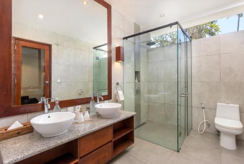 a bathroom with two sinks and a glass shower at Villa Kaniksa in Candidasa