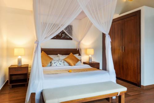 a bedroom with a white bed with curtains at Villa Kaniksa in Candidasa