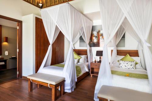 a bedroom with two beds with white drapes at Villa Kaniksa in Candidasa