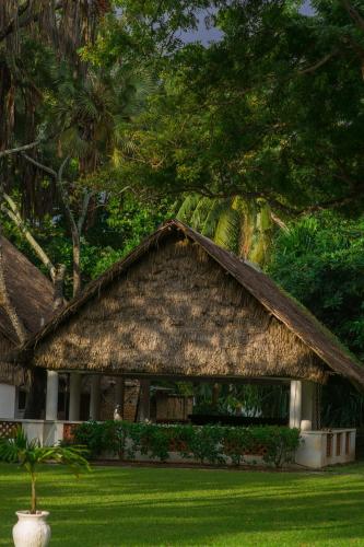 a house with a thatched roof on a lawn at Cocoa Luxury Resort, Nyali, Mombasa in Mombasa