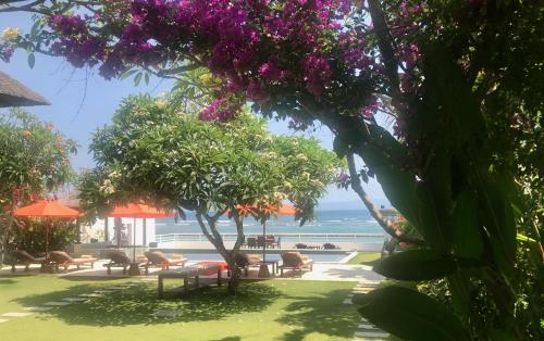 a view of the beach from a resort with purple flowers at Villa Kaniksa in Candidasa