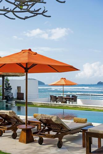 an orange umbrella and some chairs and a pool at Villa Kaniksa in Candidasa