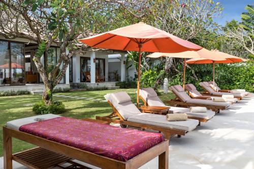 a row of lounge chairs and umbrellas on a patio at Villa Kaniksa in Candidasa