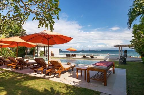 a pool with chairs and tables and an umbrella at Villa Kaniksa in Candidasa